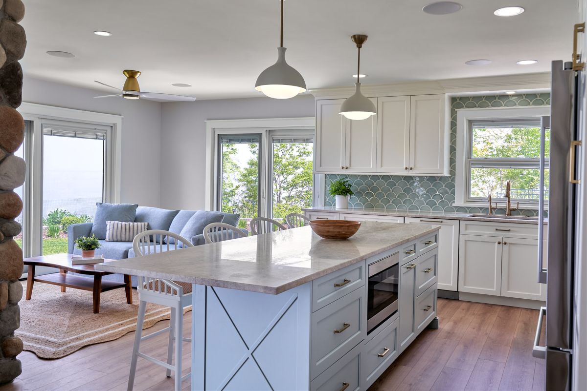 An open-concept kitchen and living room with light blue and white cabinetry, a large island, and a blue sofa.