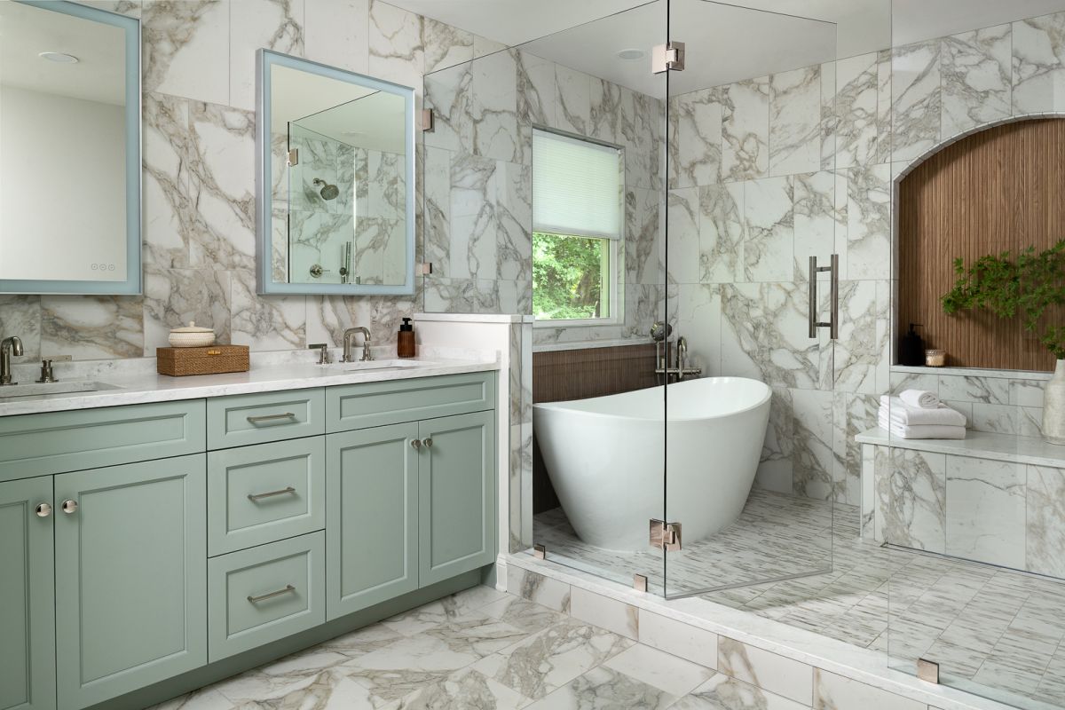 A primary bathroom with a double vanity, a freestanding tub, and a glass-enclosed shower, all featuring marble-patterned tiles.