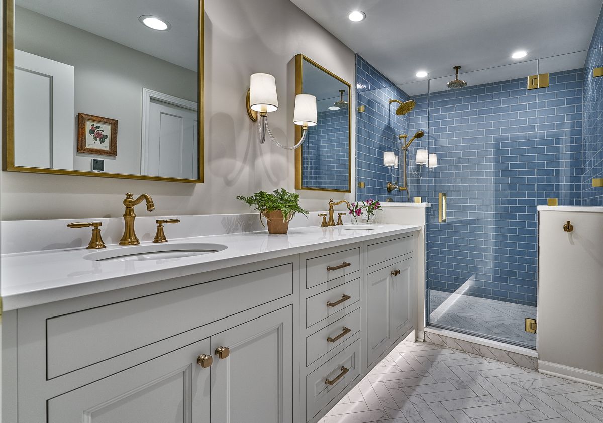 A bathroom with a double vanity, a large mirror, and a walk-in shower with blue subway tiles.