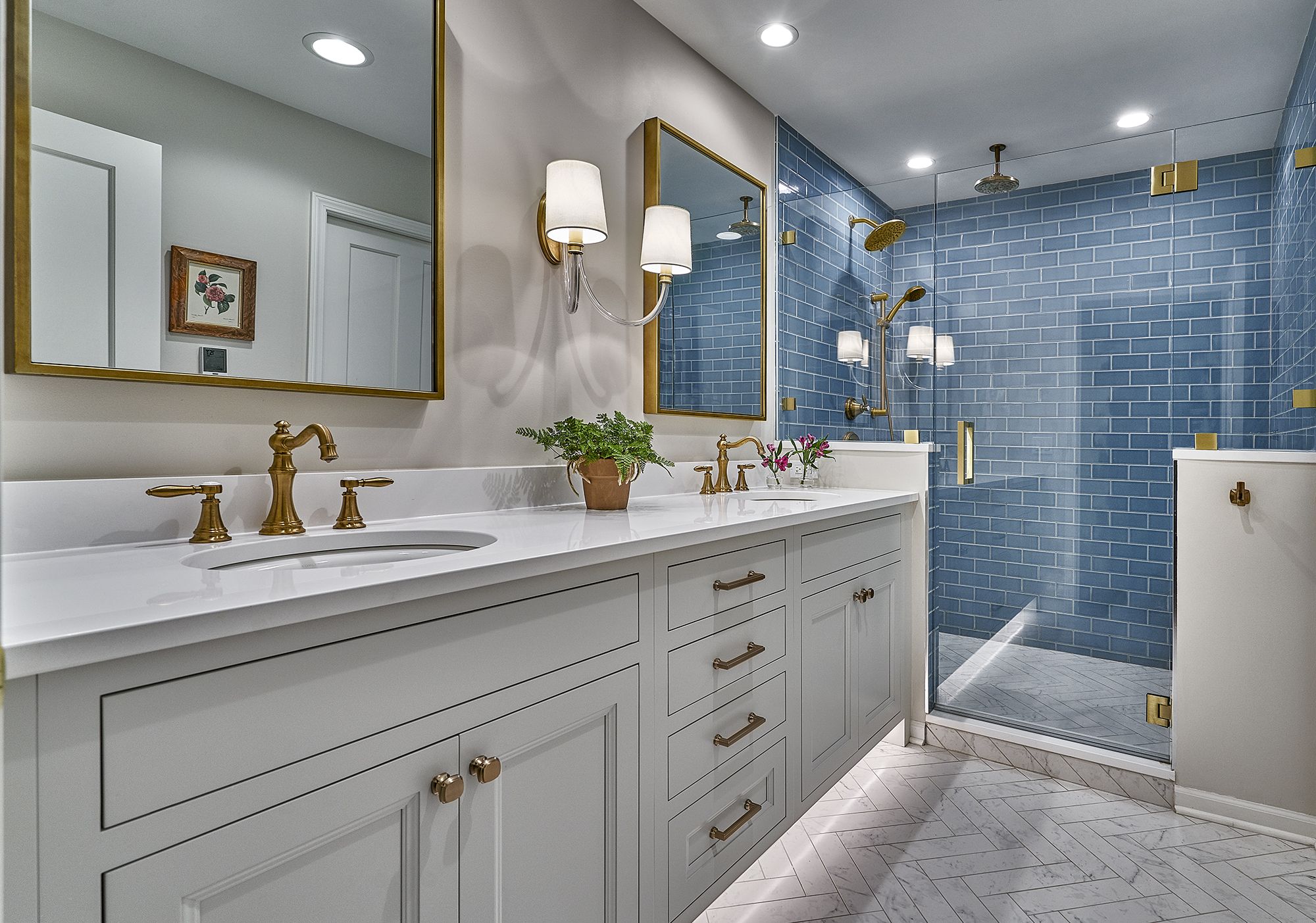 A bathroom with a double vanity, a large mirror, and a walk-in shower with blue subway tiles.