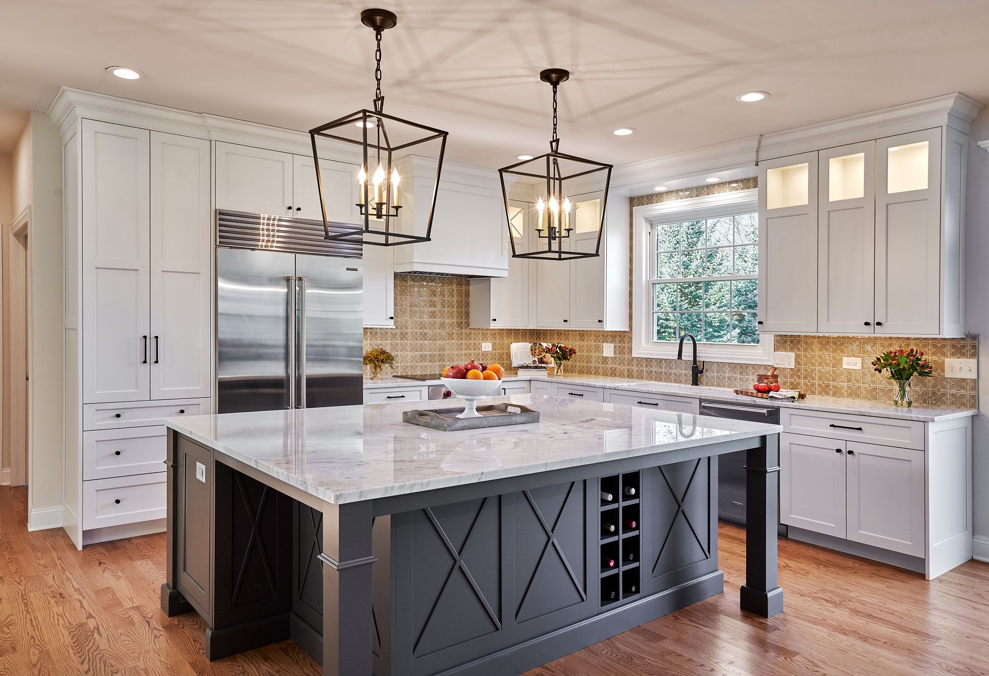 A kitchen with white upper and lower cabinets, a large gray island with a marble countertop, and stainless steel appliances.