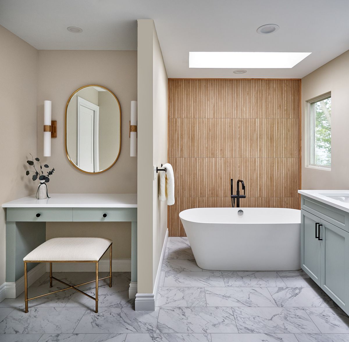 A primary bathroom features a freestanding tub, a light wood accent wall, a vanity with a makeup desk, and a double sink cabinet.