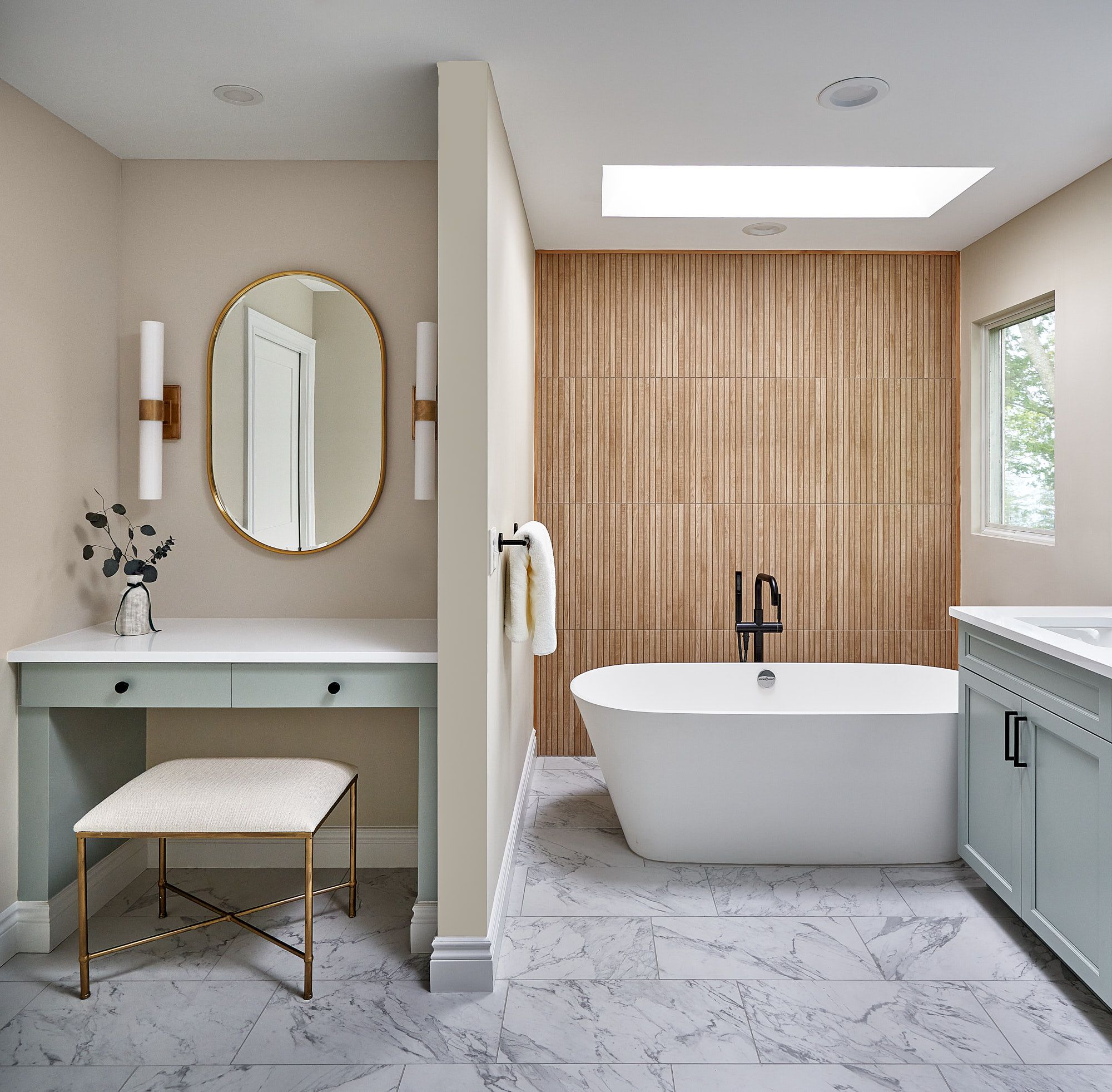 A primary bathroom features a freestanding tub, a light wood accent wall, a vanity with a makeup desk, and a double sink cabinet.